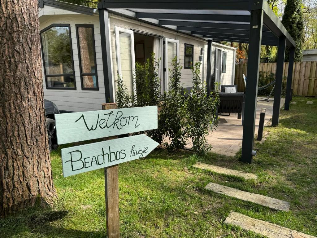 una señal frente a una casa con una señal de bienvenida en Welkom in het beachbos I Onthaasten op de Veluwe, en Hoenderloo