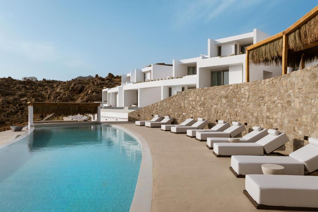 a swimming pool with lounge chairs next to a building at Mykonos Flow - Super Paradise in Super Paradise Beach