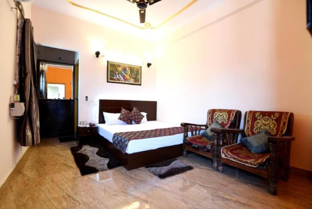 a bedroom with a bed and a chair at Hotel D S Residency Varanasi in Varanasi