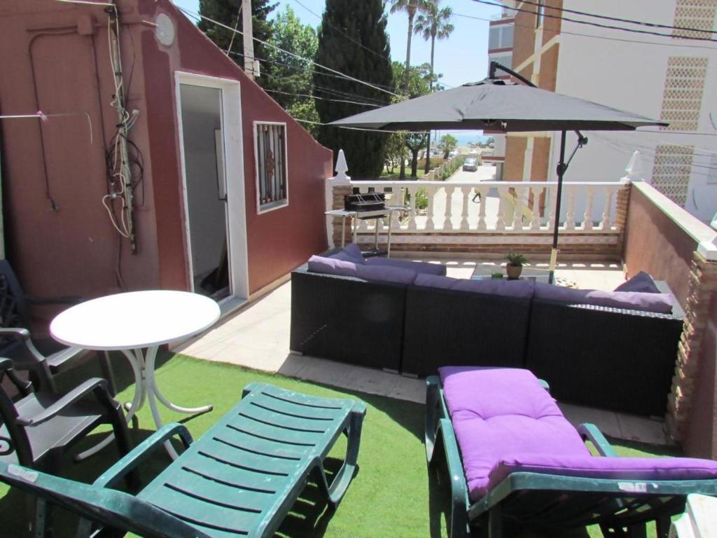 un patio con sillas, una mesa y una sombrilla en Casa ELI Casa Marenga A 150m de playa y Weekend, en Torre del Mar