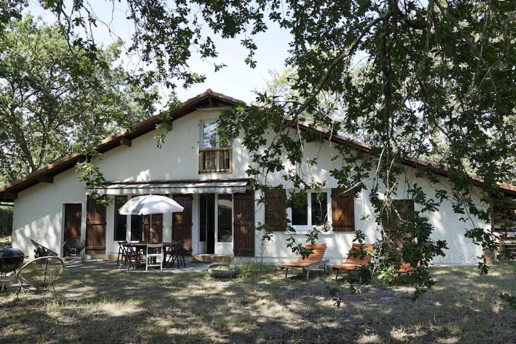 une maison blanche avec des chaises et des tables devant elle dans l'établissement Maison 8 personnes, à Mézos