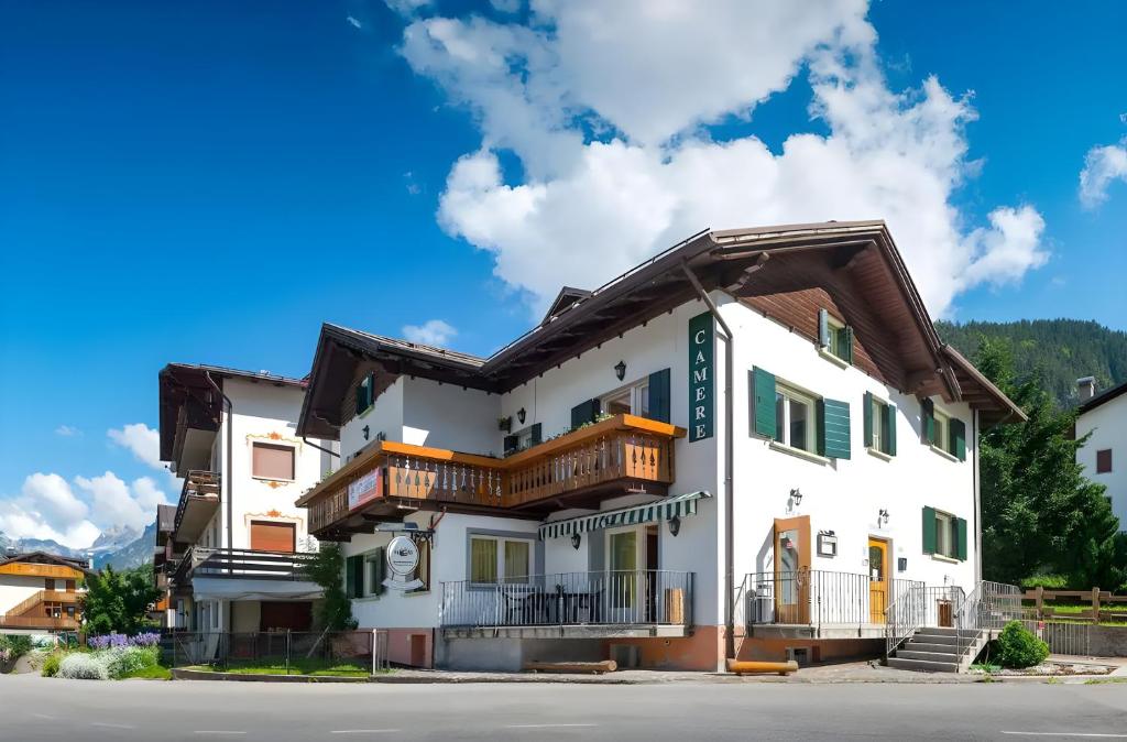 biały budynek z drewnianymi balkonami przy ulicy w obiekcie B&B Meublè Giustina w mieście Auronzo di Cadore