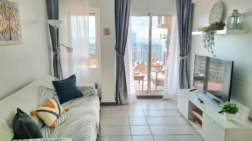 een woonkamer met een bank, een tv en een raam bij Benalmadena Minerva - Ocean view 1 Bedroom apartment in Benalmádena