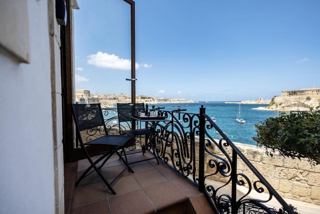 balcone con tavolo e sedie affacciato sull'acqua. di Luxurious Seaview Holiday Home in Historic Birgu a Birgu (Vittoriosa)