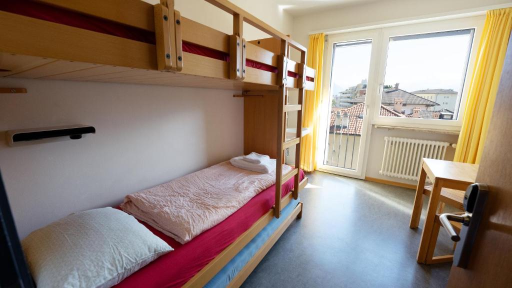 a bedroom with two bunk beds and a balcony at Locarno Youth Hostel in Locarno