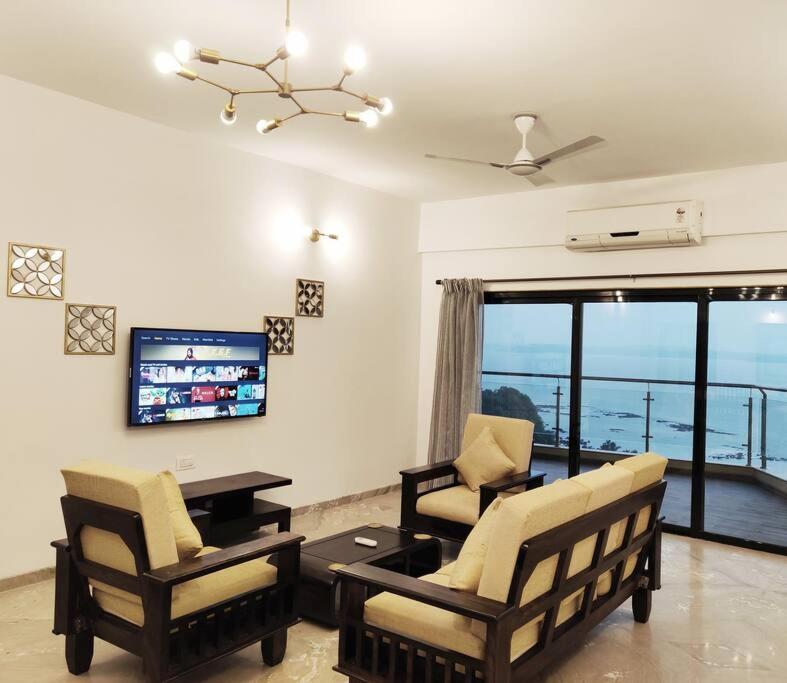 a living room with two chairs and a table and a television at Stelliam's Chic 2 Bhk Sea View Apartment in Goa in Panaji