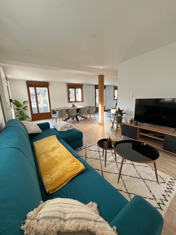 un salon avec un canapé bleu et une télévision dans l'établissement Le Balcon de Bramont, à La Bresse