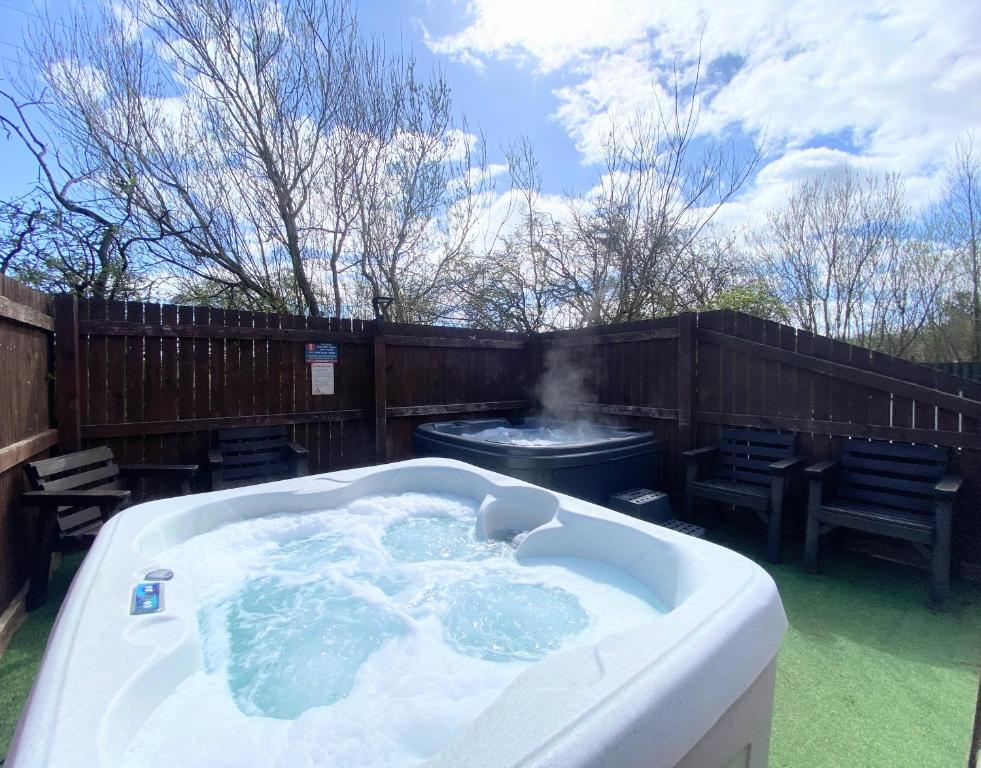 a hot tub in a backyard with a grill at Lbtie Lodge with Two Private Hot Tubs - Fife - Loch Leven - Lomond Hills in Kelty