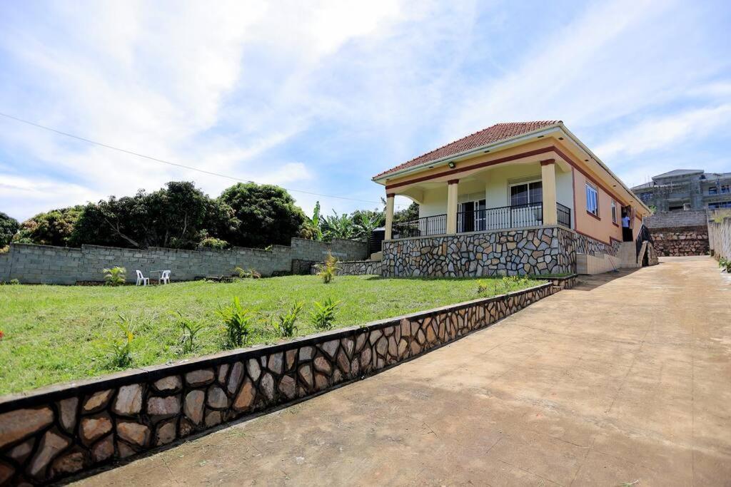 a small house with a fence next to a yard at Serene Lakeside Home in Entebbe