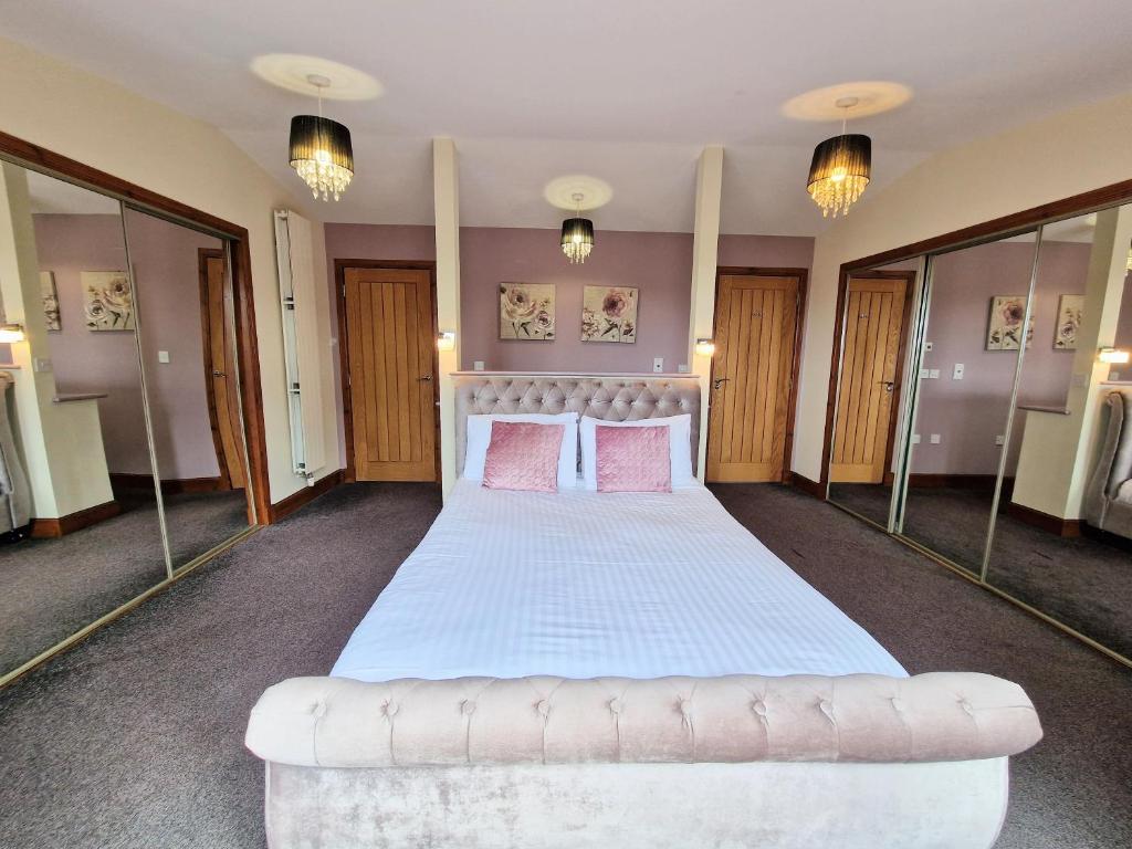 1 dormitorio grande con 1 cama grande con almohadas rosas en Torridon 1 with Private Hot Tub - Fife - Loch Leven - Lomond Hills- Pet Friendly, en Kelty