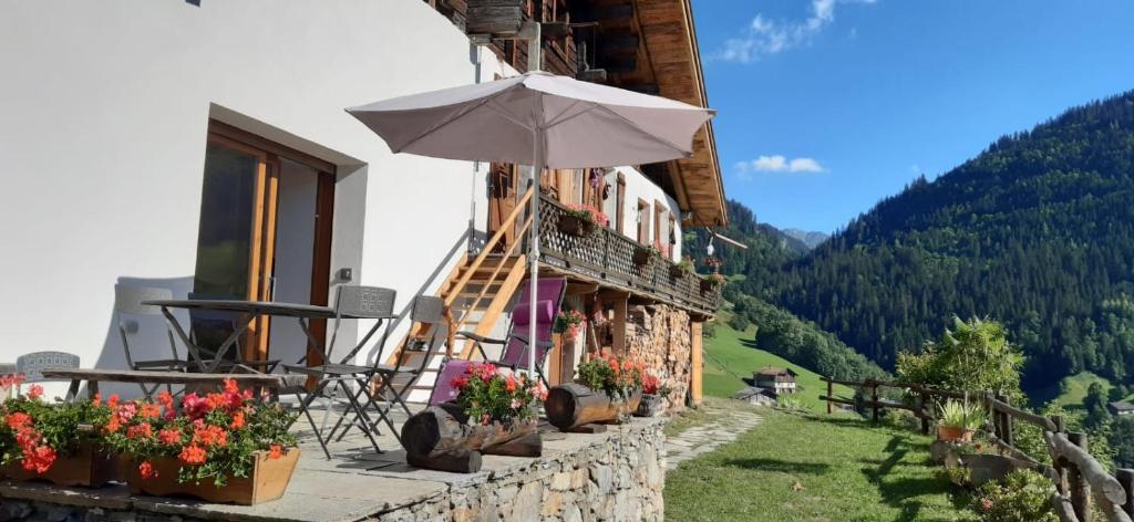 un bâtiment avec un parasol et des fleurs devant lui dans l'établissement Appartement Le Pontet Areches Beaufort, à Arêches