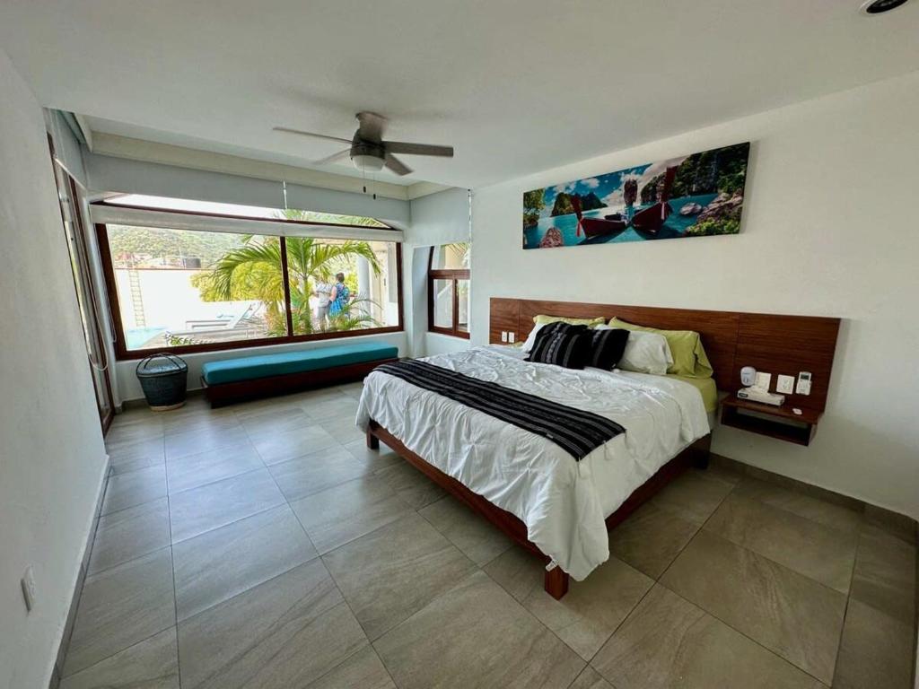 a bedroom with a bed and a large window at El Tular 2 Bdr Appartment 2 min walk from La Ropa beach in Zihuatanejo