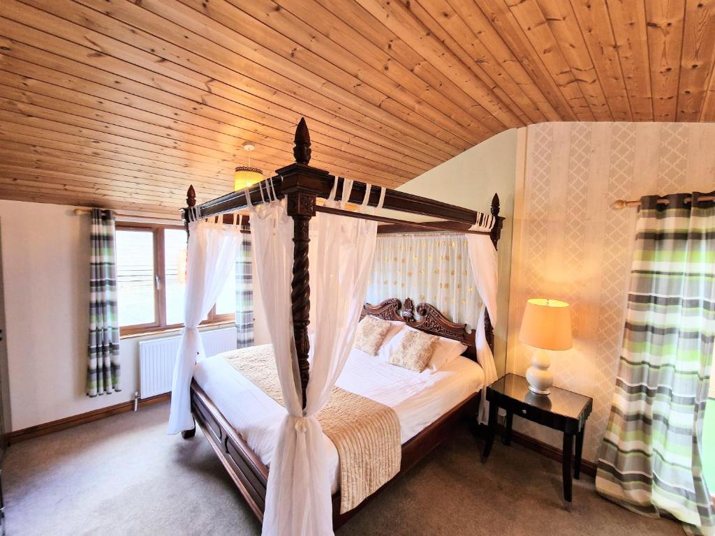 a bedroom with a canopy bed with a wooden ceiling at Lomond 3 with Private Hot Tub - Fife - Loch Leven - Lomond Hills -Pet Friendly in Kelty