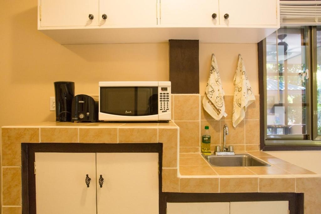 a kitchen with a microwave and a sink at M&A Riverside Beach Bungalows in Chol