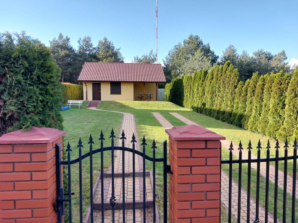um portão para um jardim com uma casa ao fundo em Domek letniskowy u Piotera Ślesin Żółwieniec em Ślesin