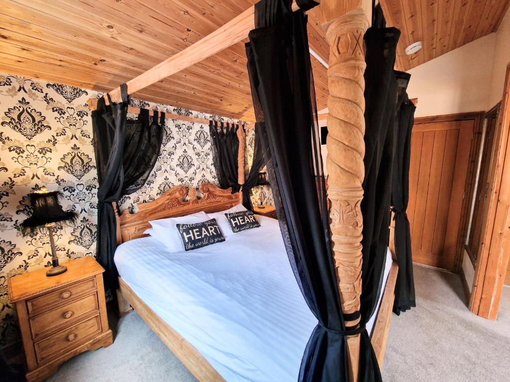 a bedroom with a canopy bed with a wooden ceiling at Lomond 2 with Private Hot Tub - Fife - Loch Leven - Lomond Hills in Kelty