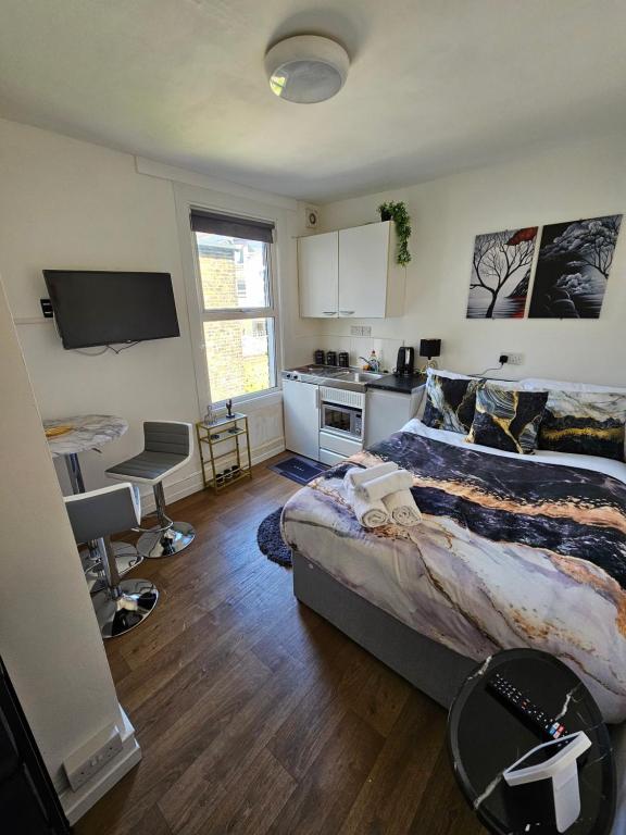 a bedroom with a bed and a desk and a kitchen at Tiny Studio, 30 min to St. Pancras, North London in London