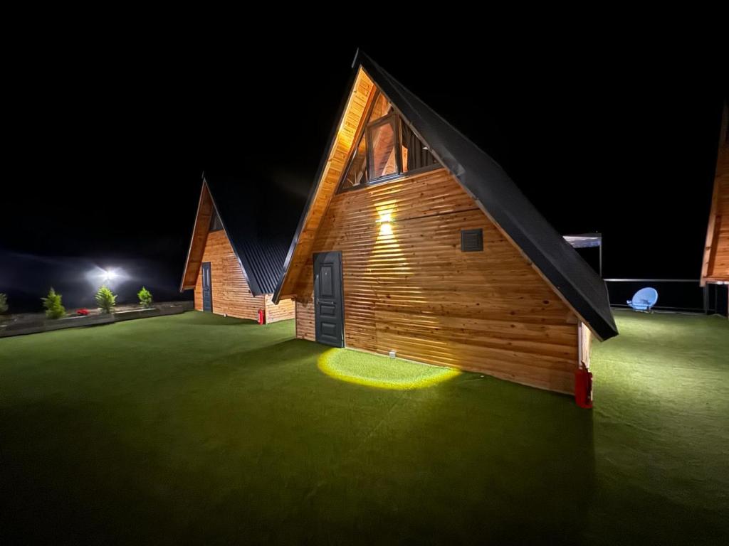 a wooden house with a green lawn at night at ERTUTATİLEVLERi in Dalaman