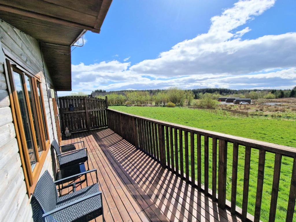 a deck with two chairs and a view of a field at Lomond 4 with Private Hot Tub - Fife - Loch Leven - Lomond Hills in Kelty