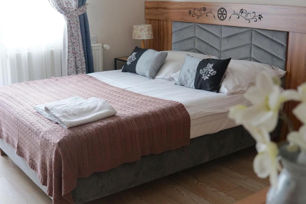 - une chambre avec un grand lit et une tête de lit en bois dans l'établissement Pokoje Gościnne Pod Lipą, à Zakopane
