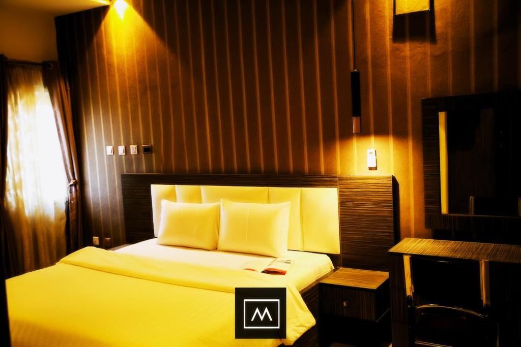 a hotel room with a bed with a yellow bedspread at MO-House Hotels and Apartments Mabushi in Abuja