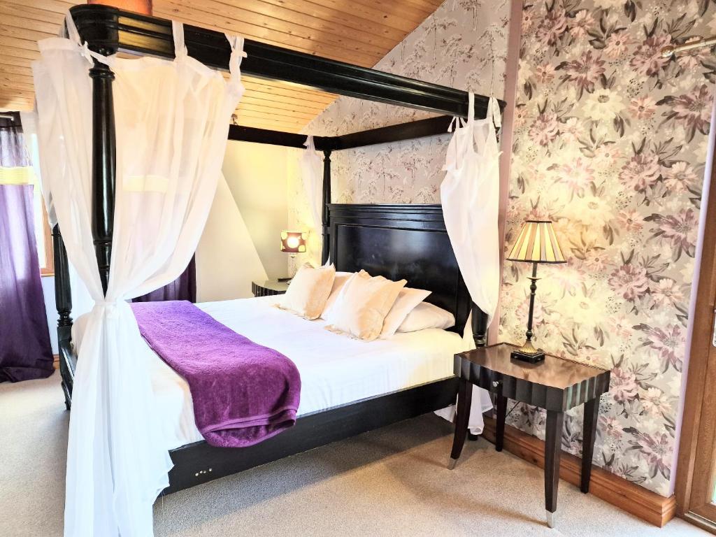 ein Schlafzimmer mit einem Himmelbett und einer lila Decke in der Unterkunft Ochil 8 with Private Hot Tub - Fife - Loch Leven - Lomond Hills in Kelty