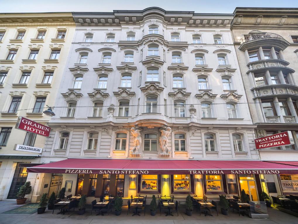 um grande edifício branco com mesas e cadeiras em frente em Graben Hotel em Viena