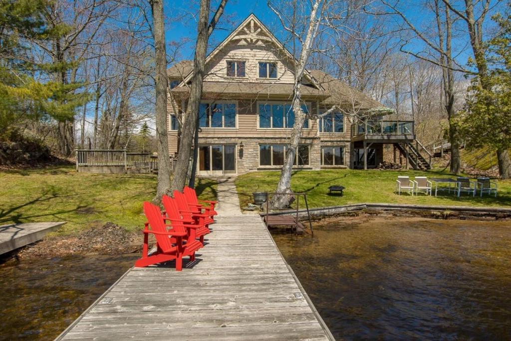 a group of red chairs on a dock in front of a house at Endless Summers Fabulous Lake oasis in Port Severn
