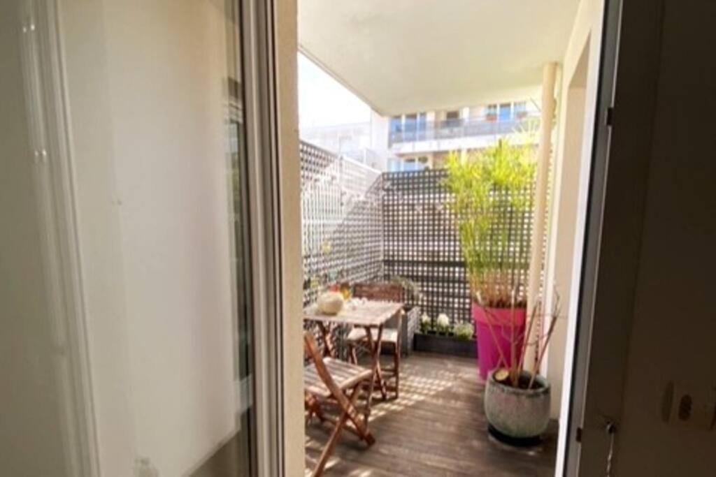 een open deur naar een patio met een tafel en stoelen bij Appartement de standing calme idéal pour les JO ! in Suresnes