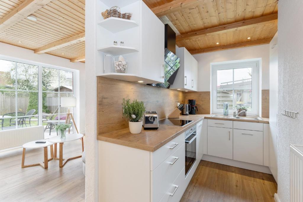 a kitchen with white cabinets and a wooden ceiling at Deich-Bungalow Königsberger Allee 30 APPARTO Grömitz in Grömitz