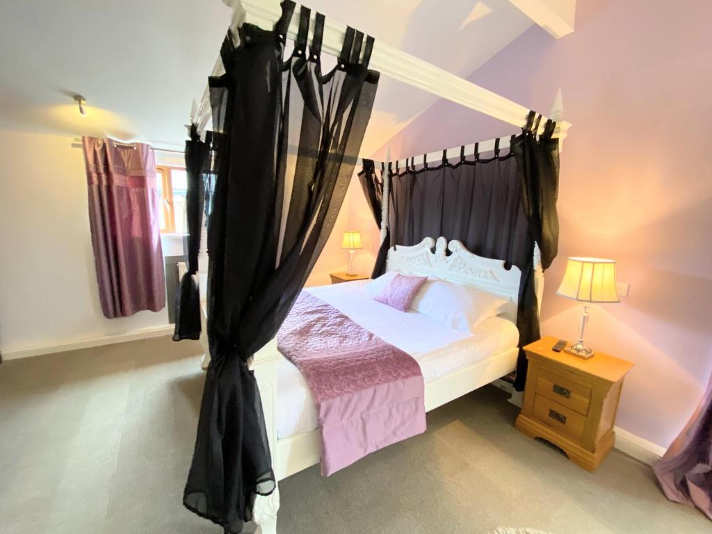 a bedroom with a canopy bed with black curtains at Ochil 10 with Private Hot Tub - Fife - Loch Leven - Lomond Hills in Kelty