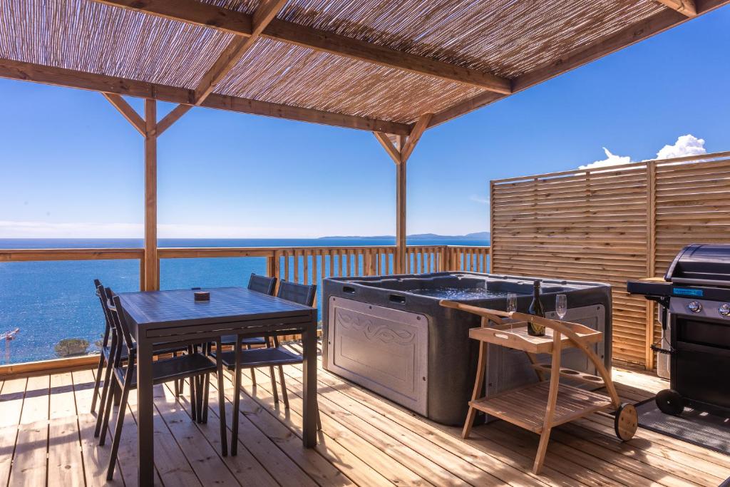 eine Terrasse mit einem Grill, einem Tisch und Stühlen in der Unterkunft Domaine Ile d'or, bungalow Segur 8 in Saint-Raphaël