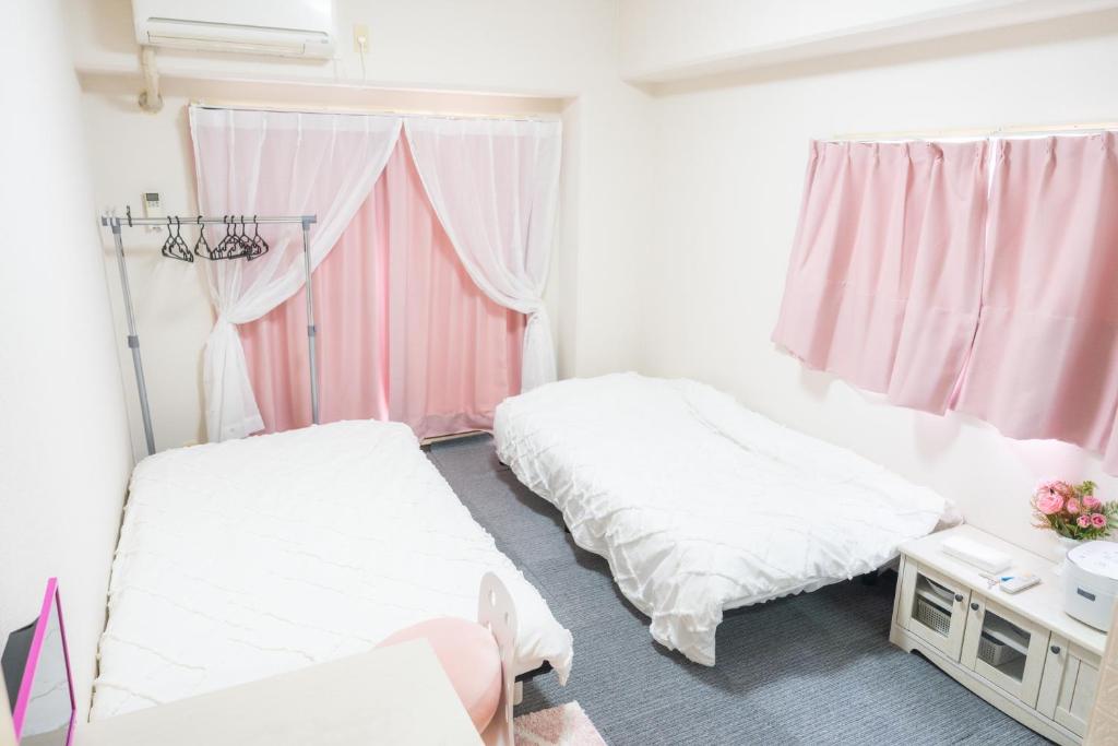 2 camas en una habitación con cortinas rosas en coco eleele 901, en Osaka