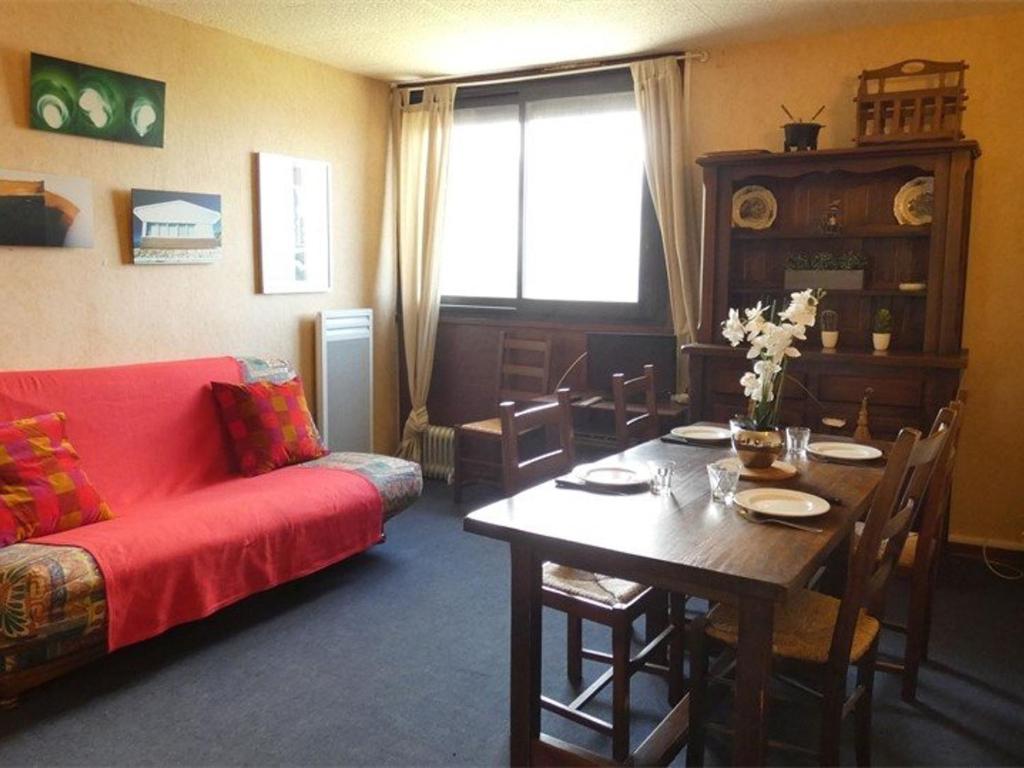 a living room with a table and a red couch at Studio Saint-Lary-Soulan, 1 pièce, 4 personnes - FR-1-457-254 in Saint-Lary-Soulan