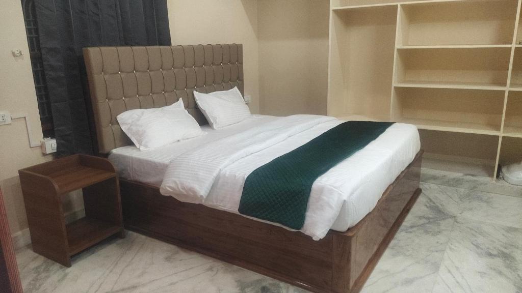 a bedroom with a large bed with white and green sheets at Avinash residency in Bhadrāchalam