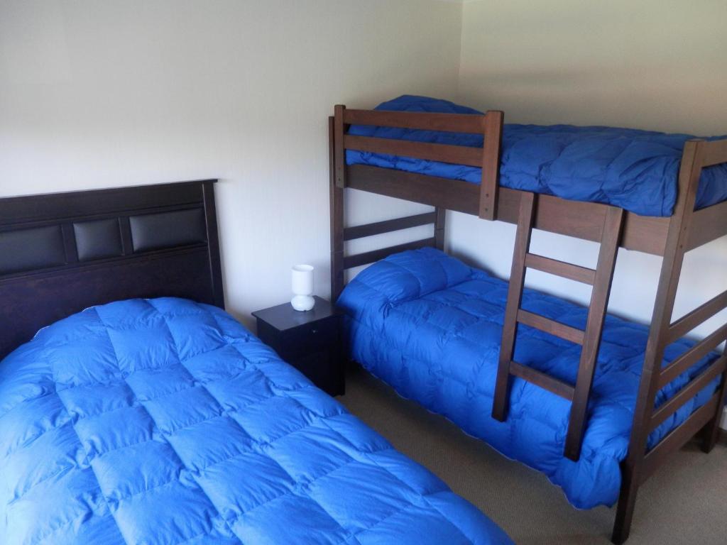 a bedroom with two bunk beds with blue sheets at Casa Costa Pucón in Pucón