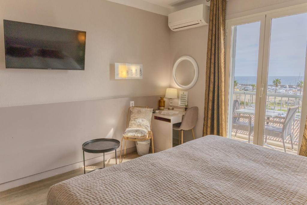 a bedroom with a bed and a desk and a window at Hotel Maquis et Mer in Sari Solenzara