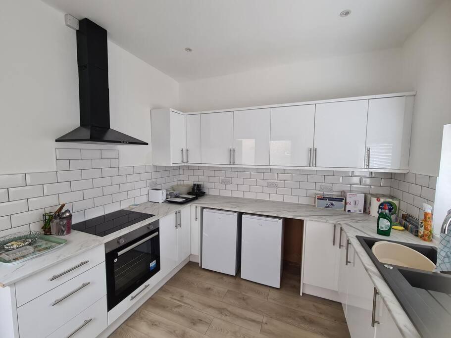 una cocina blanca con armarios blancos y fregadero en Newly Renovated Coastal Property, en Llanelli