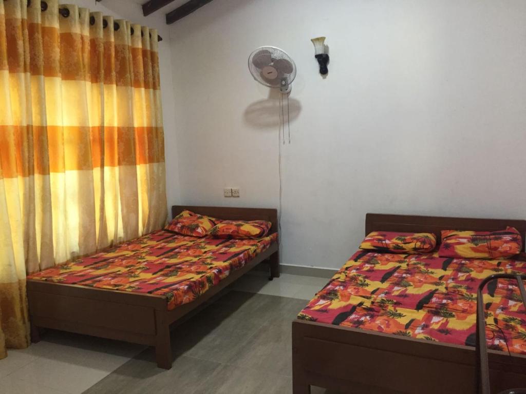 a bedroom with two beds and a fan at Henas Revrstone Holiday in in Matale