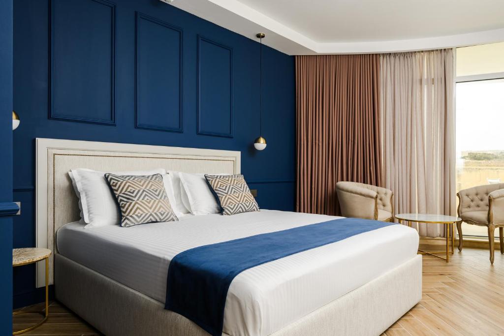 - une chambre avec un grand lit aux murs bleus dans l'établissement XVI Suites - Adults Only, à Naxxar