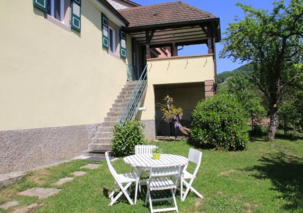- une table et des chaises dans la cour d'une maison dans l'établissement Gite Les Glycines au coeur de l'Alsace, à Albé