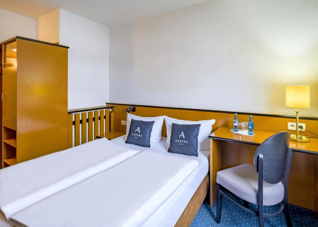a bedroom with a bed and a desk and a chair at Aspire Frankfurt Airport, Trademark Collection by Wyndham in Rüsselsheim