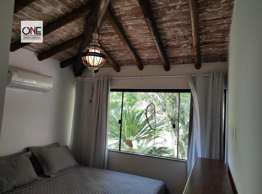 a bedroom with a bed and a large window at Casa espetacular na praia Brava in Búzios