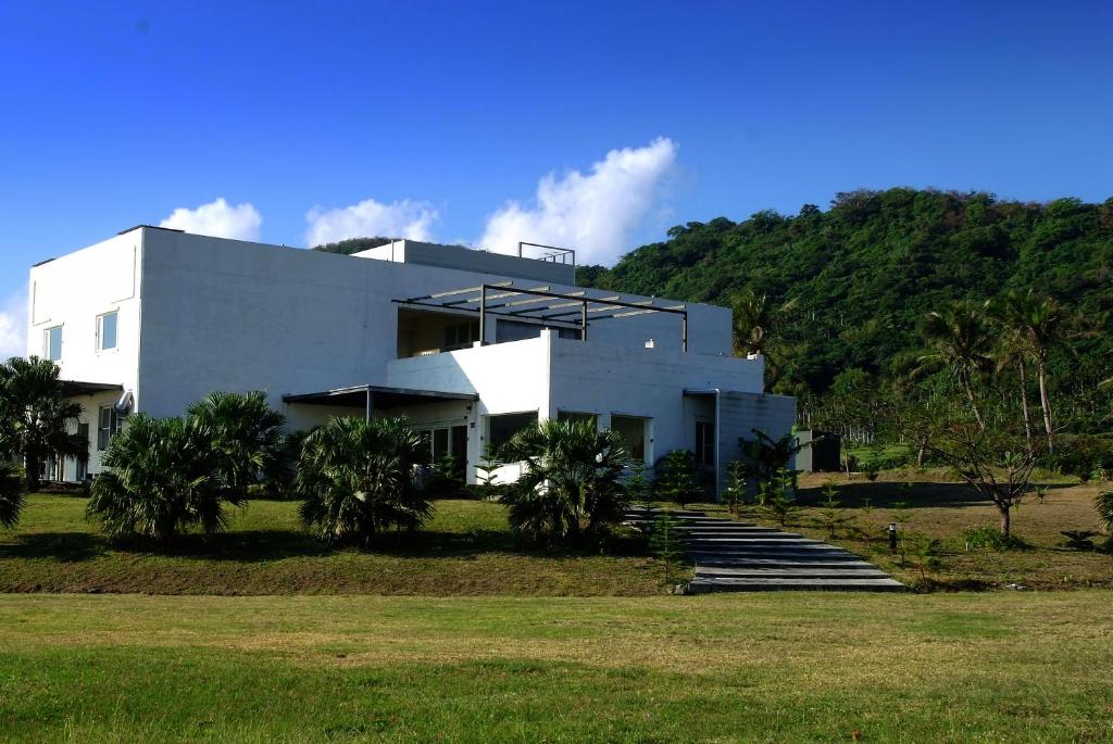 a white building with stairs in front of a hill at The Blue Lagoon B&amp;B in Fengbin