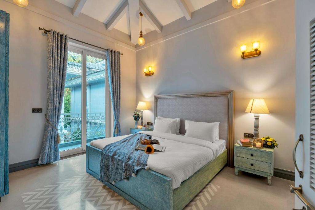 1 dormitorio con cama y ventana grande en Staymaster Salsa Sunset Pvt Pool 4BHK Lux, en Saligao