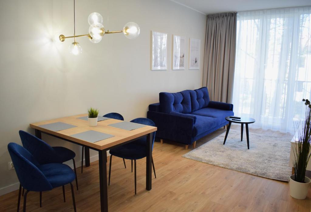 a living room with a table and a blue couch at Apartos Seaside Garden Apartments I in Świnoujście
