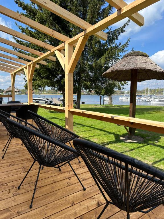 two chairs and an umbrella on a wooden deck at Domki Marina Rydzewo in Rydzewo