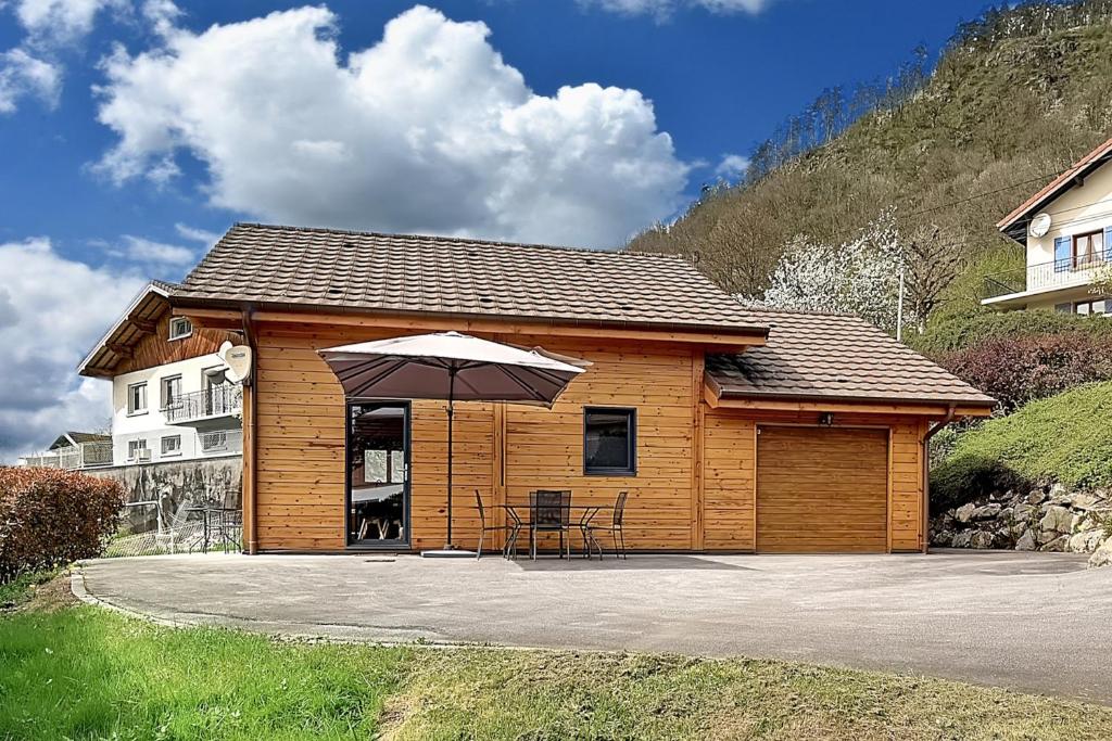 eine Hütte mit einem Sonnenschirm, einem Tisch und Stühlen in der Unterkunft Chalet Bois Cosy - Climatisé - Piscine privée in Ferdrupt