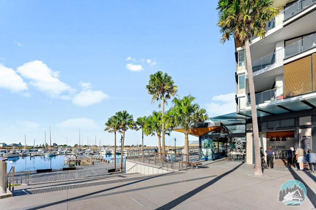 a marina with palm trees and a building at Aircabin - Shell Cove - Waterview - 2 Bed Apt in Shellharbour