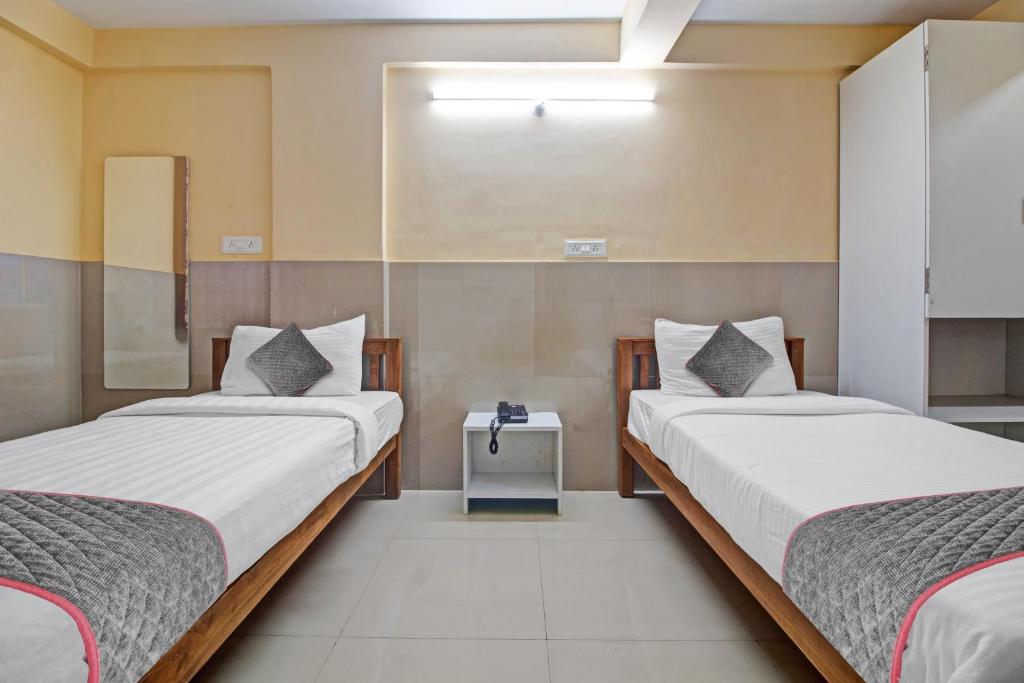 a bedroom with two beds and a nightstand between them at Super Townhouse 1266 Empire Executive in Pune